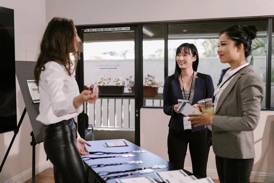 Opret Virksomhed på Amager: CVR og Skatteregler Guide 1 Businesswomen registering at a conference desk, smiling and interacting in a professional setting.